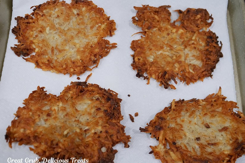 Fried hash brown patties on a baking sheet lined with paper towels.