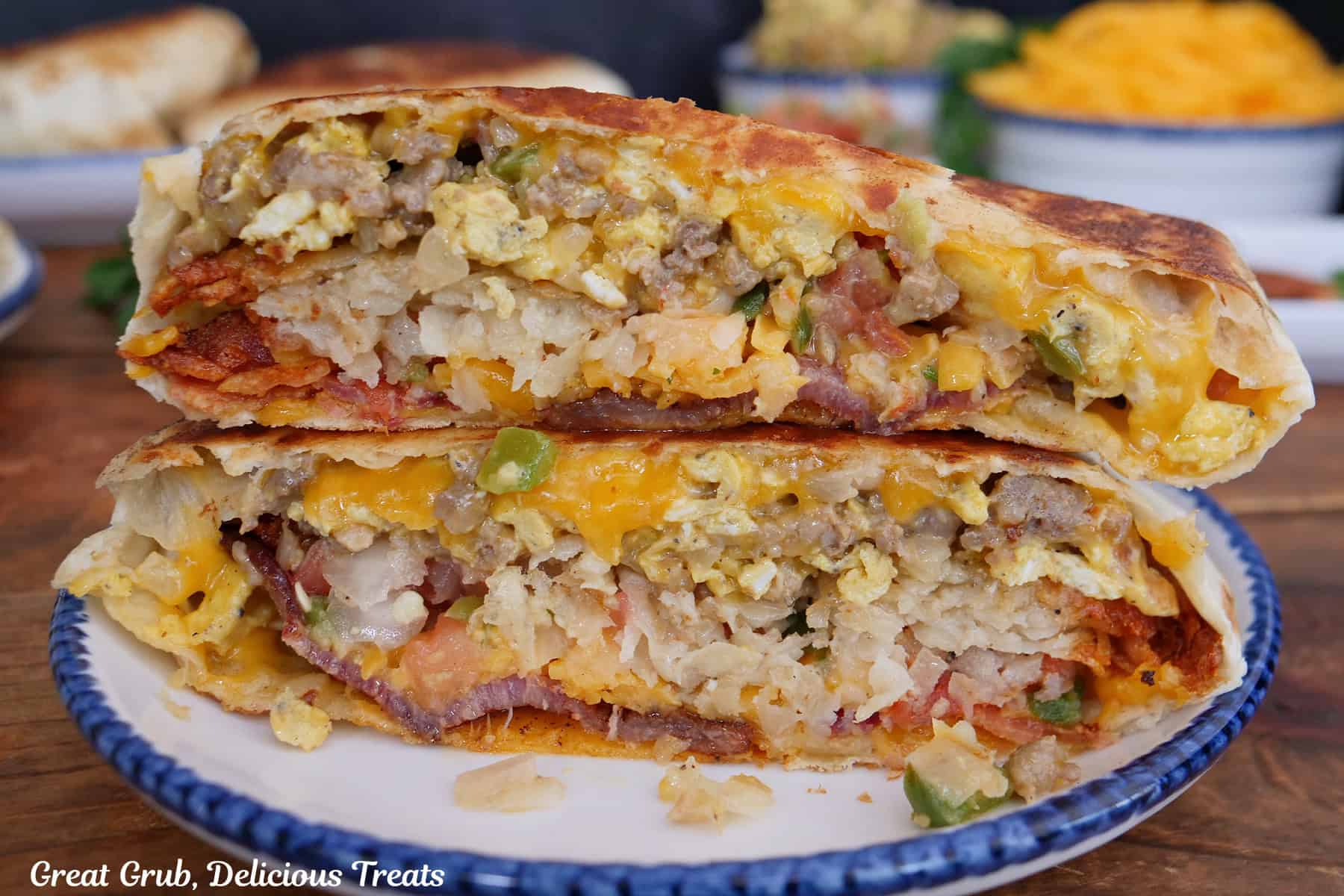 A white round plate with blue trim with a breakfast crunch wrap on it that has been cut in half and stacked on top of each other.