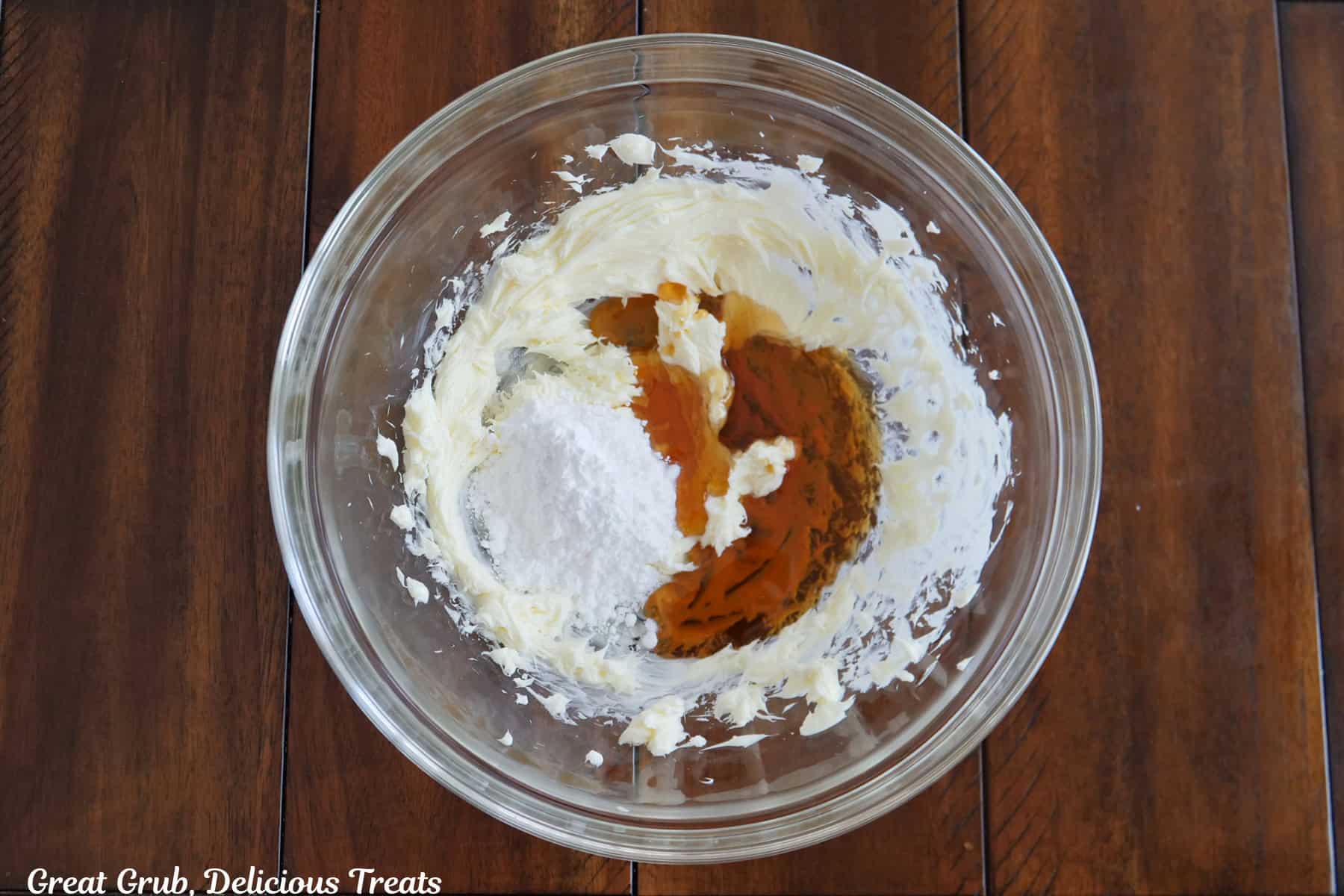 A wood surface with a glass bowl with all the ingredients in it to make honey butter.