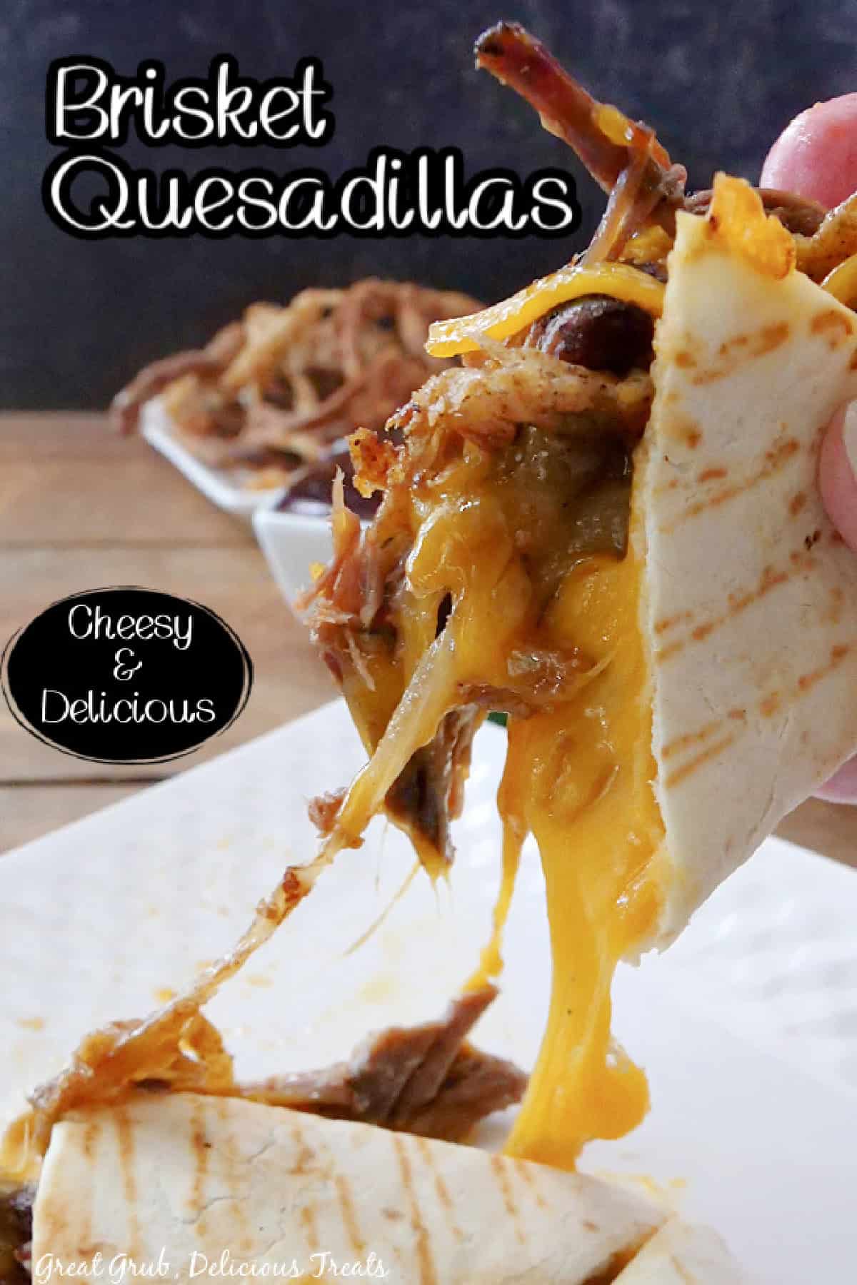 A piece of a cheesy brisket quesadilla being picked up off a white plate showing the cheese pull, and a title overlay at the top.
