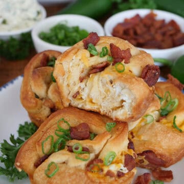A round white plate with blue trim with four cheesy jalapeno popper muffins on it with a title overlay at the top.