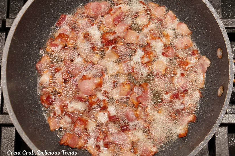 A frying pan with lots of pieces of bacon cooking in it.