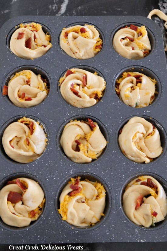 A 12 count muffin tin with cheesy jalapeno popper muffins in it before being baked.