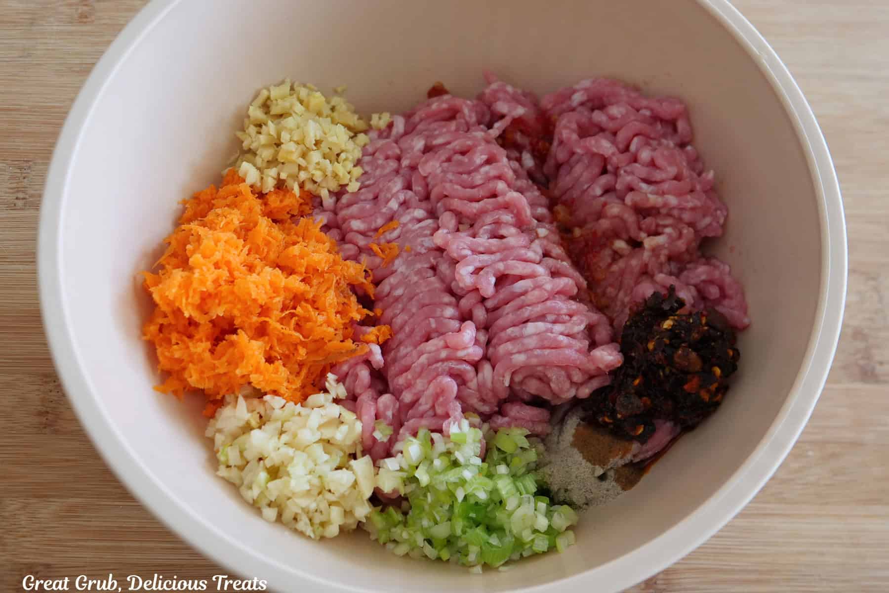 A light colored bowl filled with all the pork ingredients for the chili crisp pork potstickers.