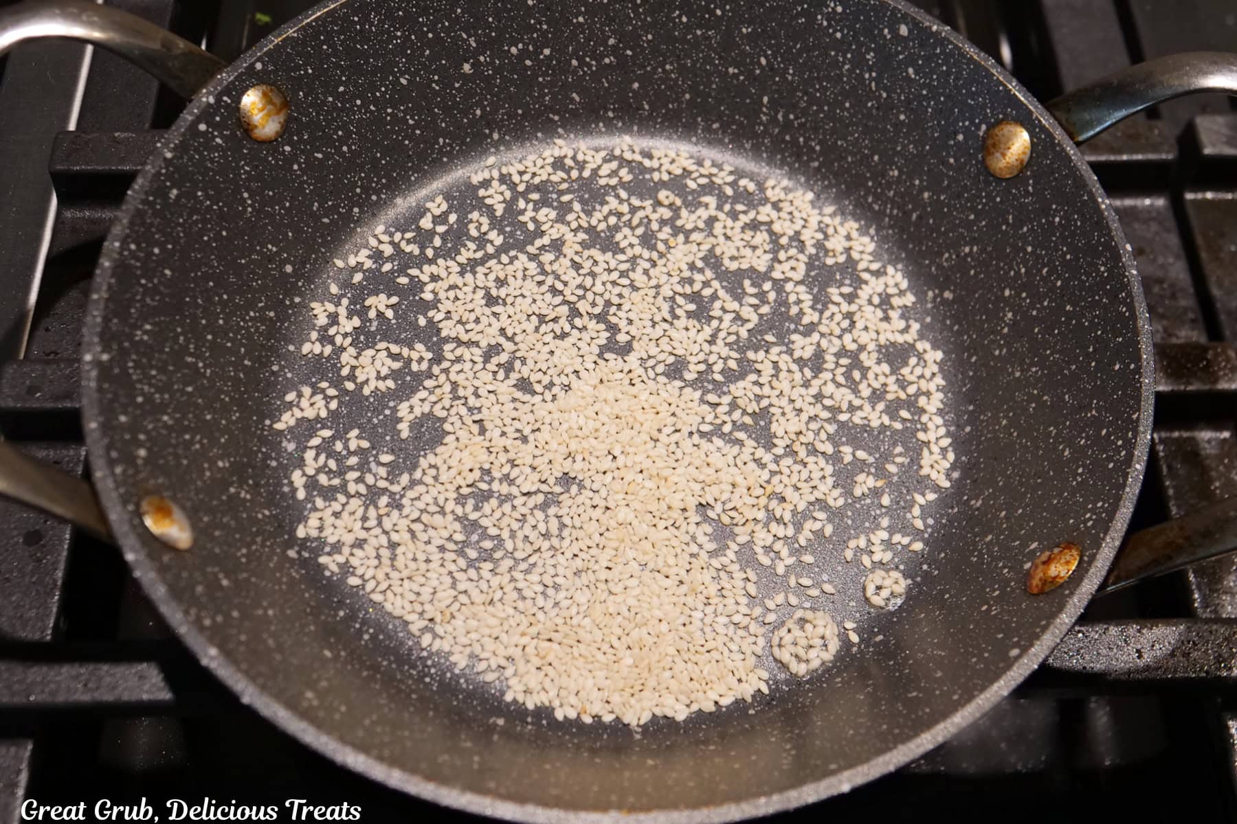 A frying pan with toasted sesame seeds in it.