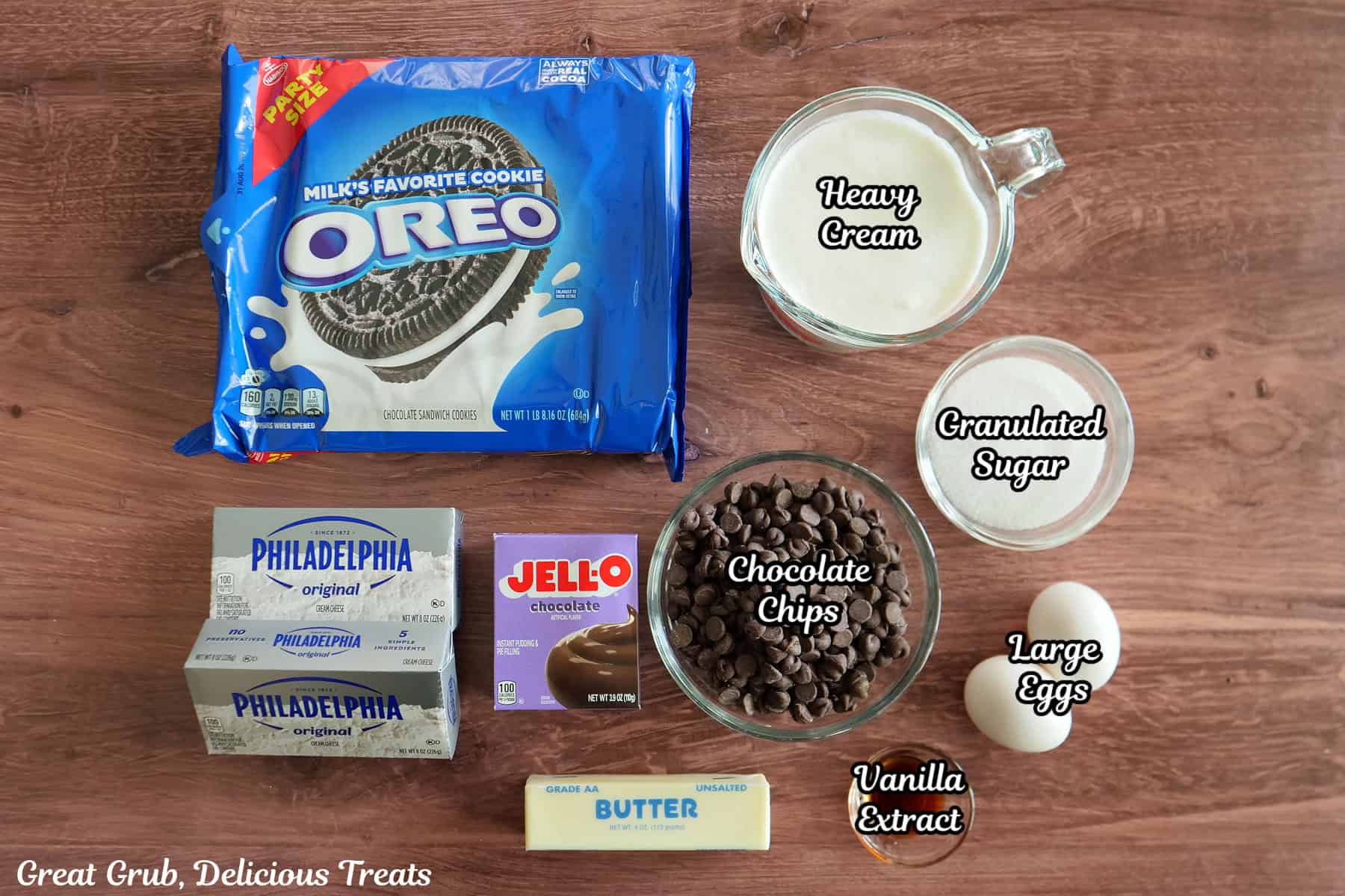 A wood surface with all the ingredients on it to make chocolate crunch mini cheesecakes.