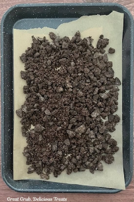 A parchment lined baking sheet with the chocolate crunch mixture spread evenly on it ready to be baked.