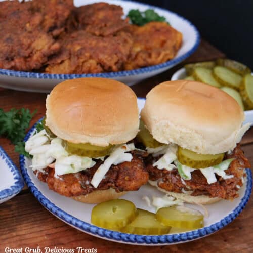 A wood surface with two Nashville hot chicken sliders on it.