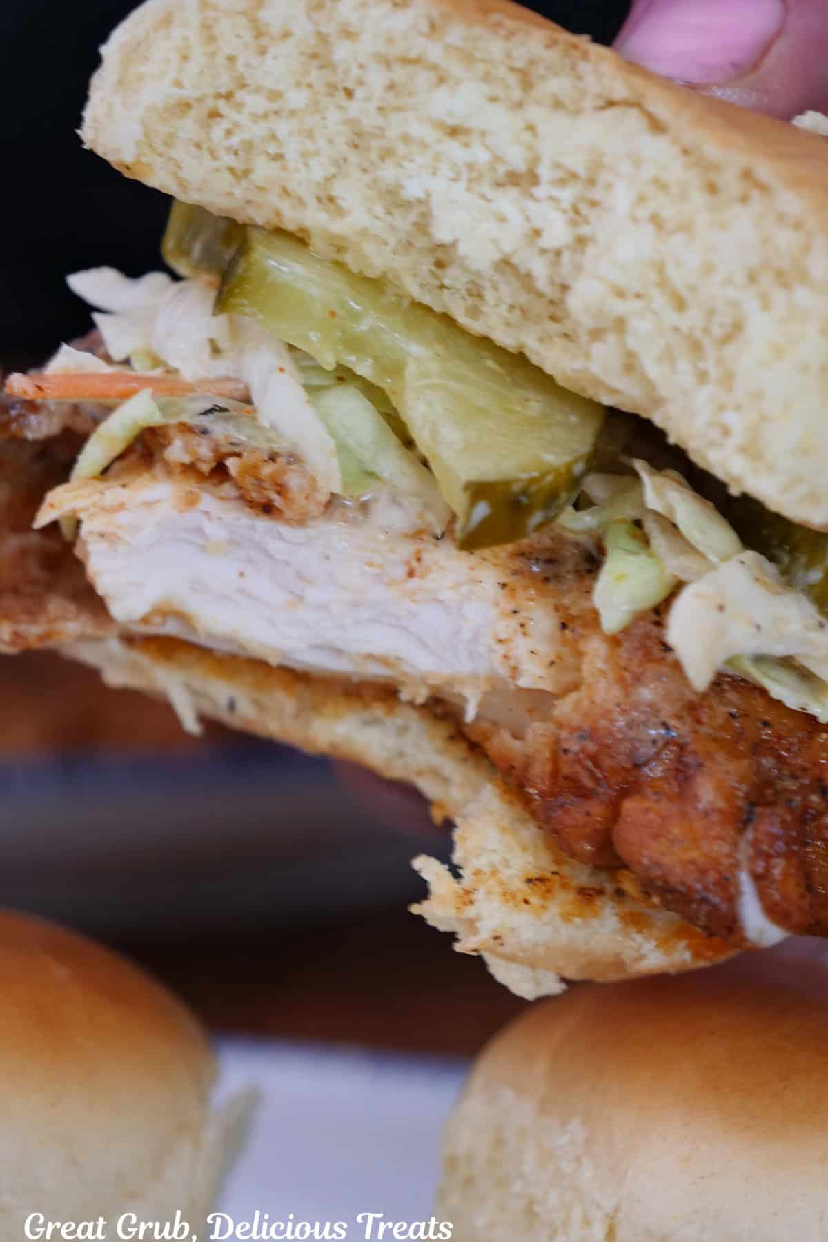 A Nashville hot chicken slider held up with a bite taken out of it.
