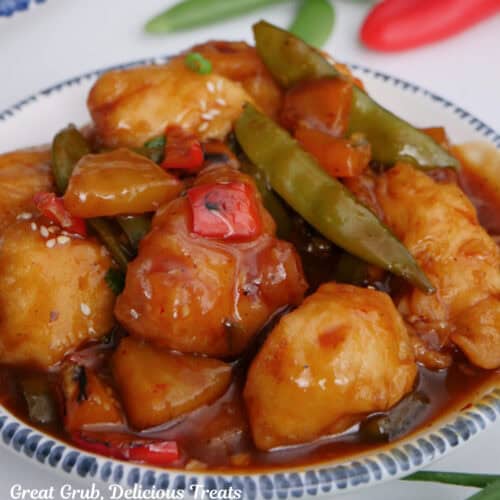 A white bowl with blue trim filled with a serving of spicy chicken stir-fry in it.