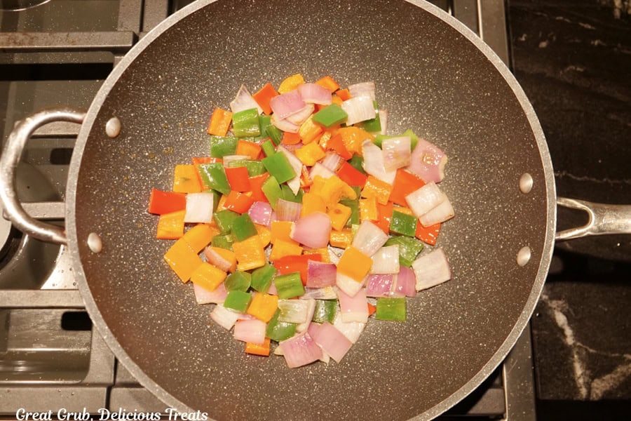 A frying pan with onions and bell pepper being sauteed.