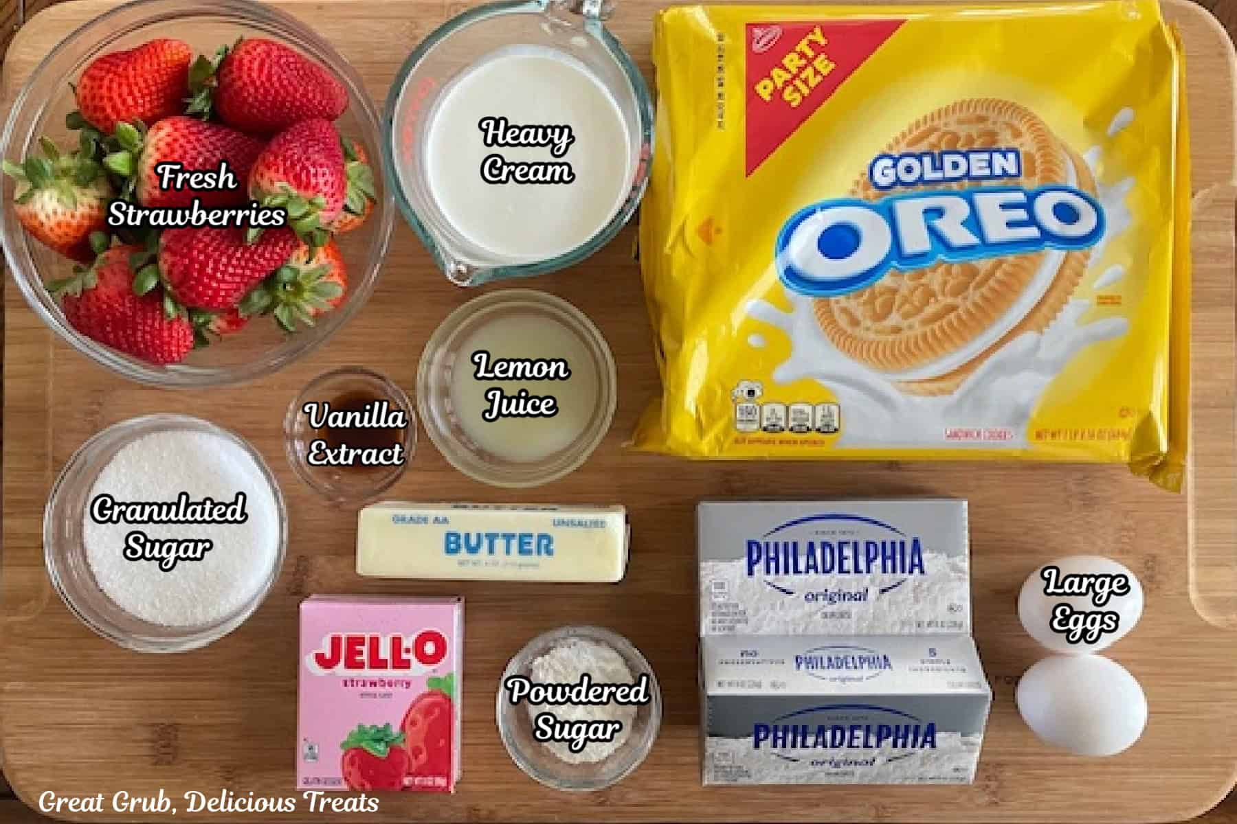 A wood surface with all the ingredients on it to make strawberry crunch cheesecake bites.