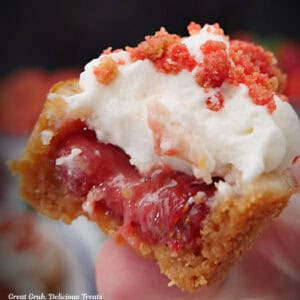 A mini strawberry crunch cheesecake bite with a bite taken out of it.