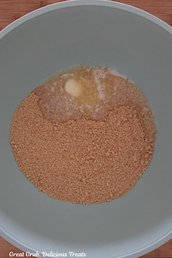 A light blue bowl with cookie crust ingredients in it before being mixed together.