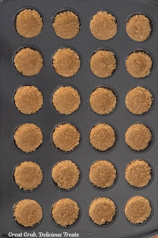 A 24-count mini muffin pan with a cookie crust pressed into each of the 24 spots.