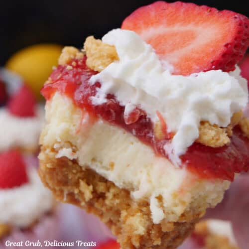 A mini strawberry lemon crunch cheesecake held up with a bite taken out of it, and a title overlay at the top.