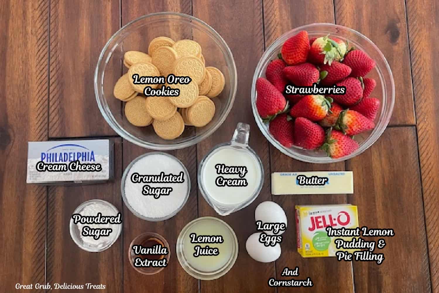A wood surface with all the ingredients to make strawberry lemon crunch mini cheesecakes on it.
