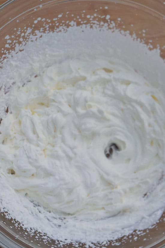 A mixing bowl with heavy whipping cream beat with the start of stiff peaks forming.