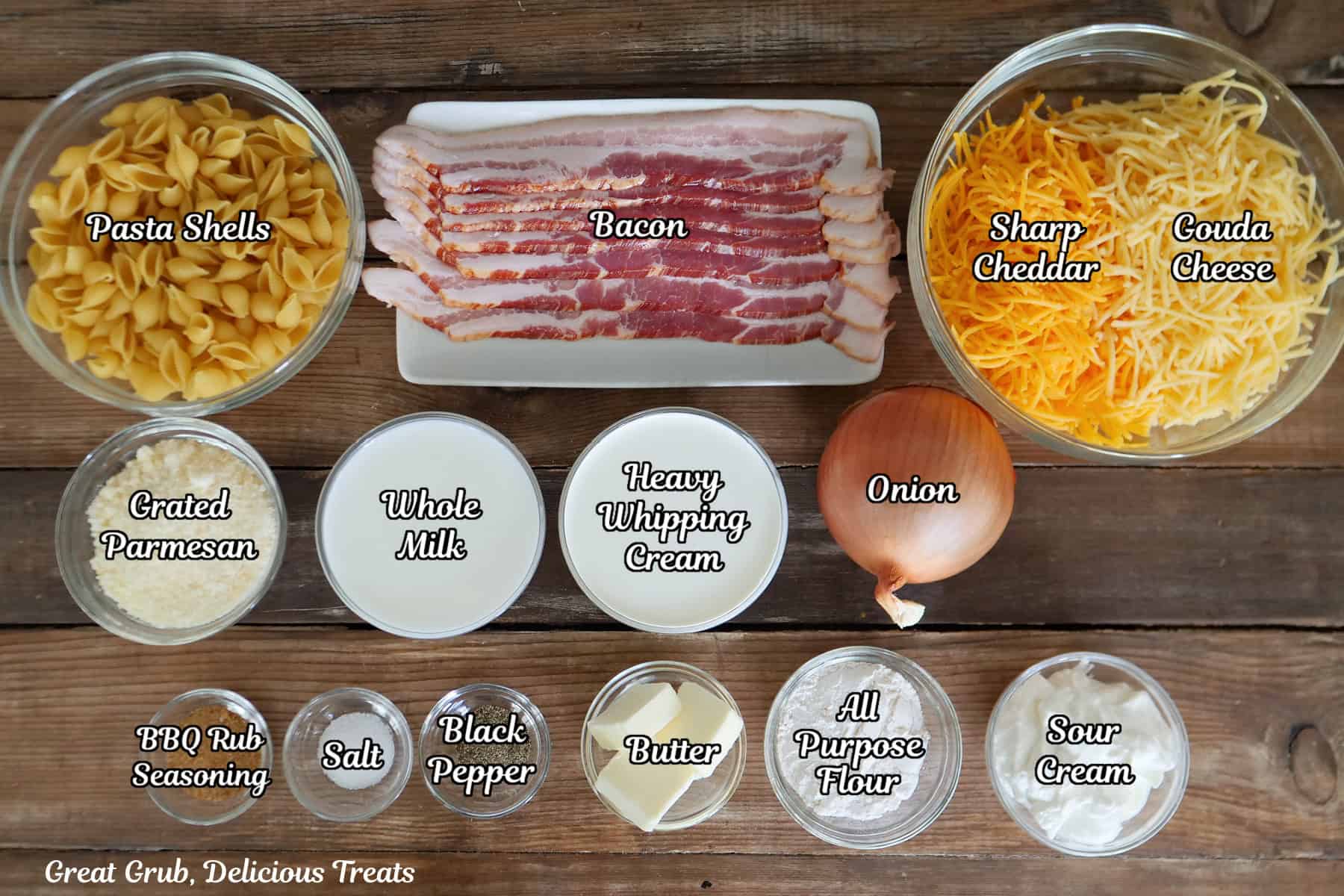 A wood surface with all the ingredients needed to make creamy bacon mac and cheese placed on it.