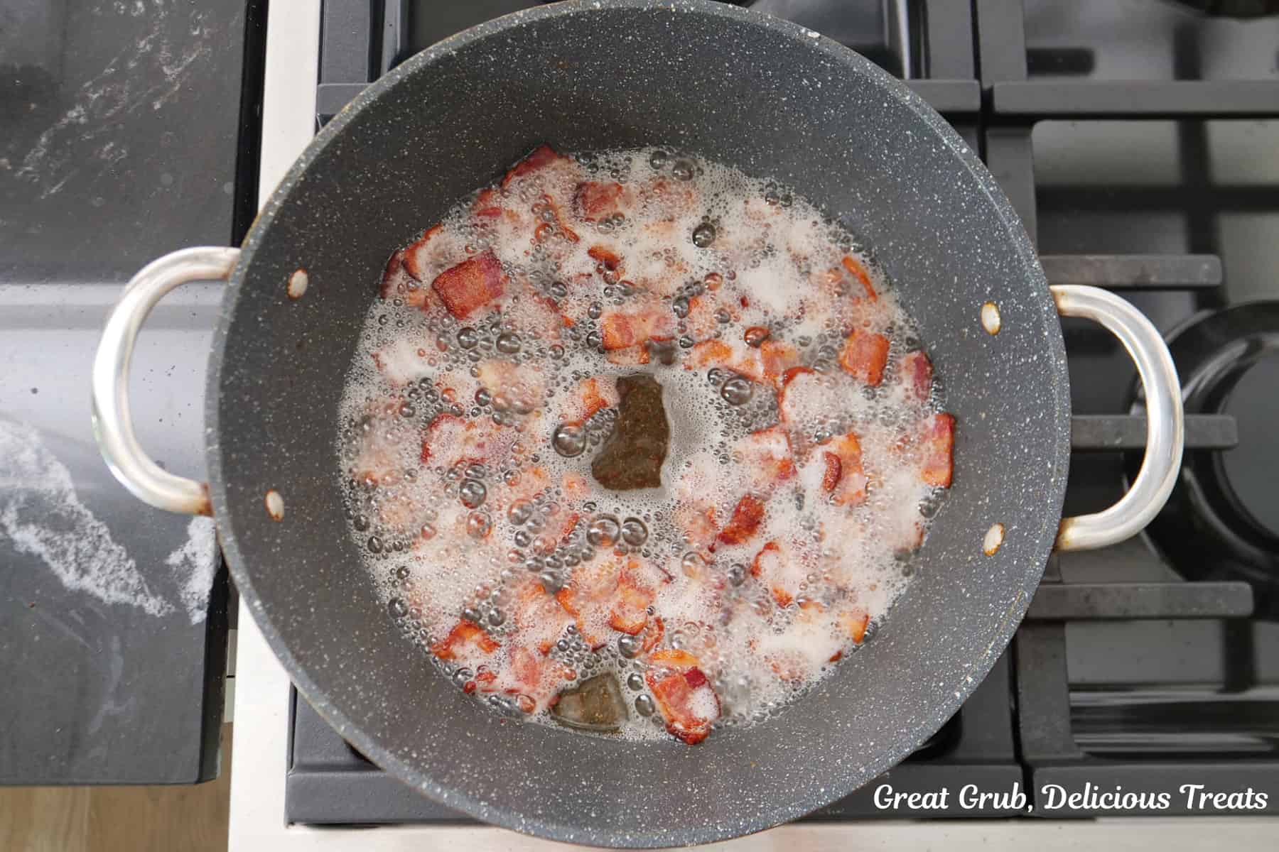 A frying pan with pieces of bacon cooking in it.