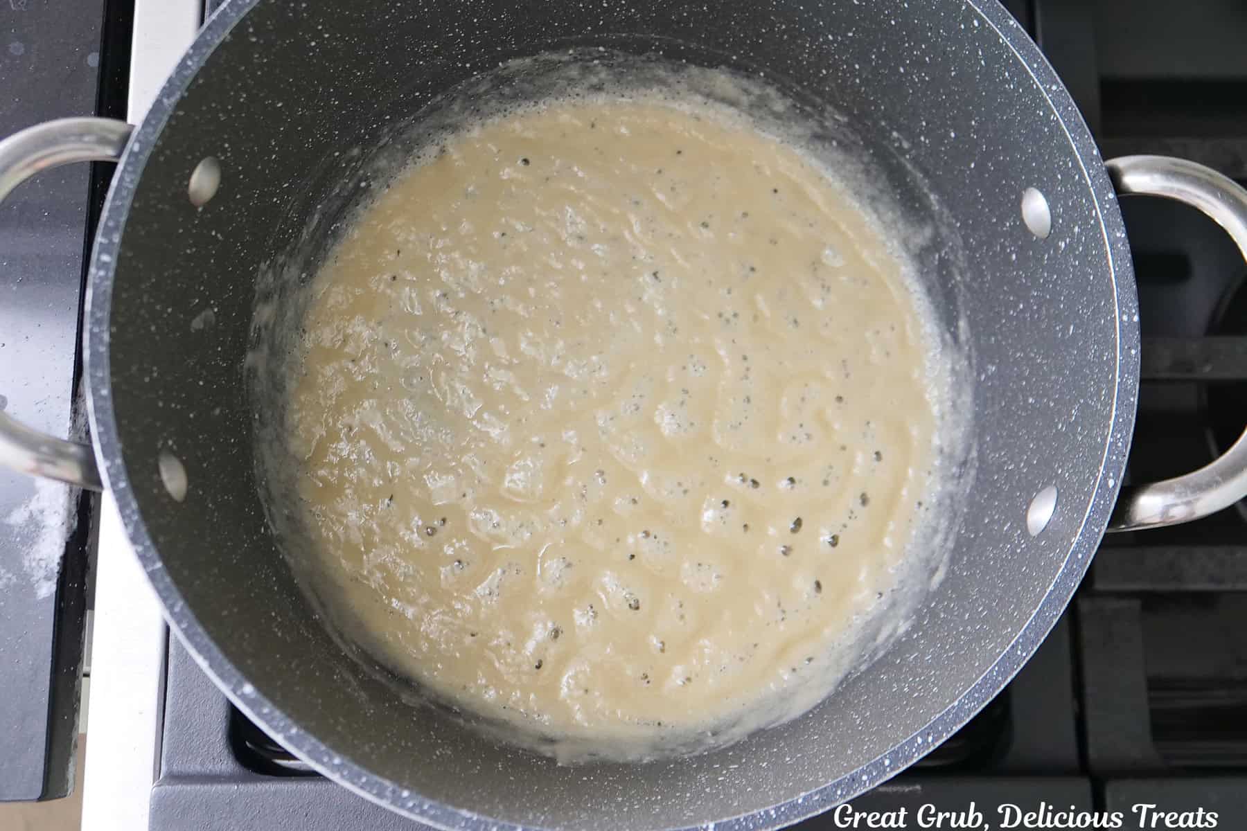 A frying pan with a roux being started and is boiling in the pan.