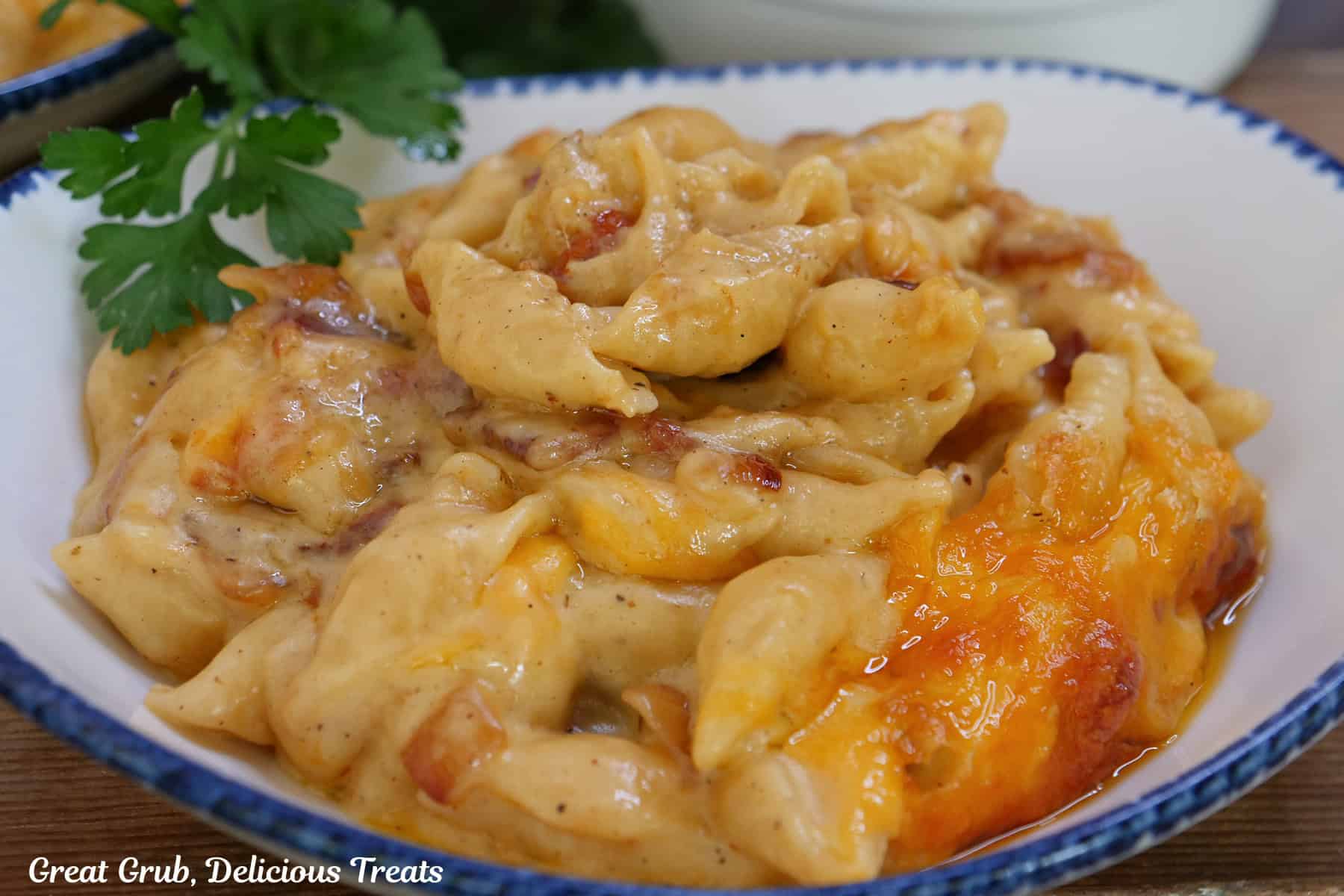 A white bowl with blue trim with a serving of bacon mac and cheese in it.