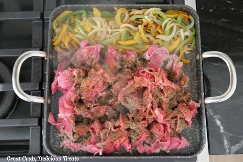 A grill pan with the grilled onions and peppers, and the shaved beef added to the pan.