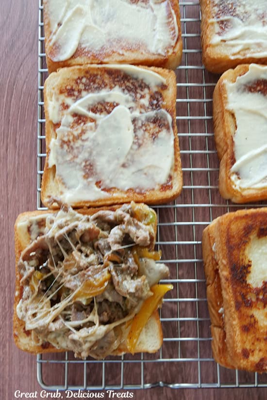 A wire rack with the grilled toast topped with the cheesesteak mixture.