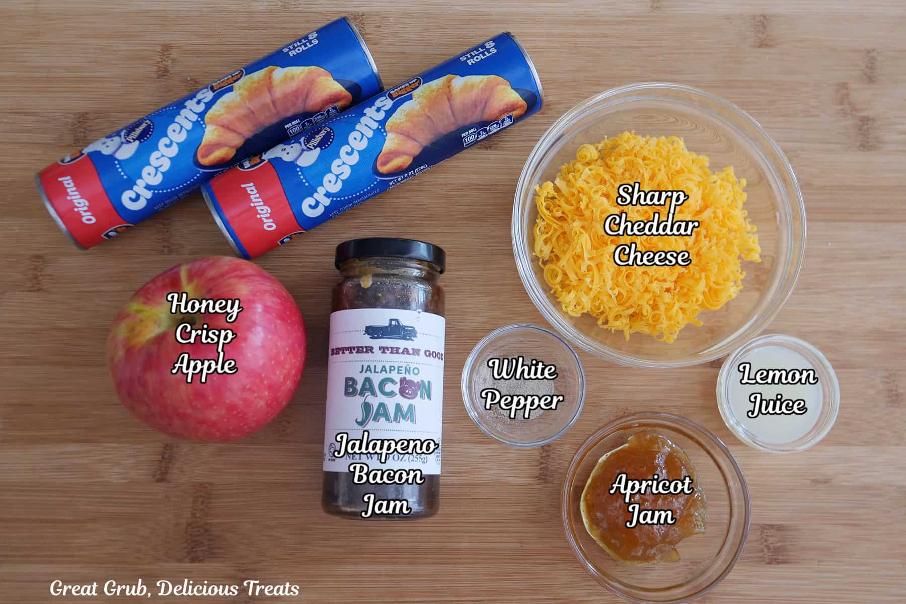 A wood surface with all the ingredients on it to make cheesy apple bacon jam roses.