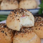 A round white plate with blue trim with five everything bagel bombs on it with a title overlay at the top.