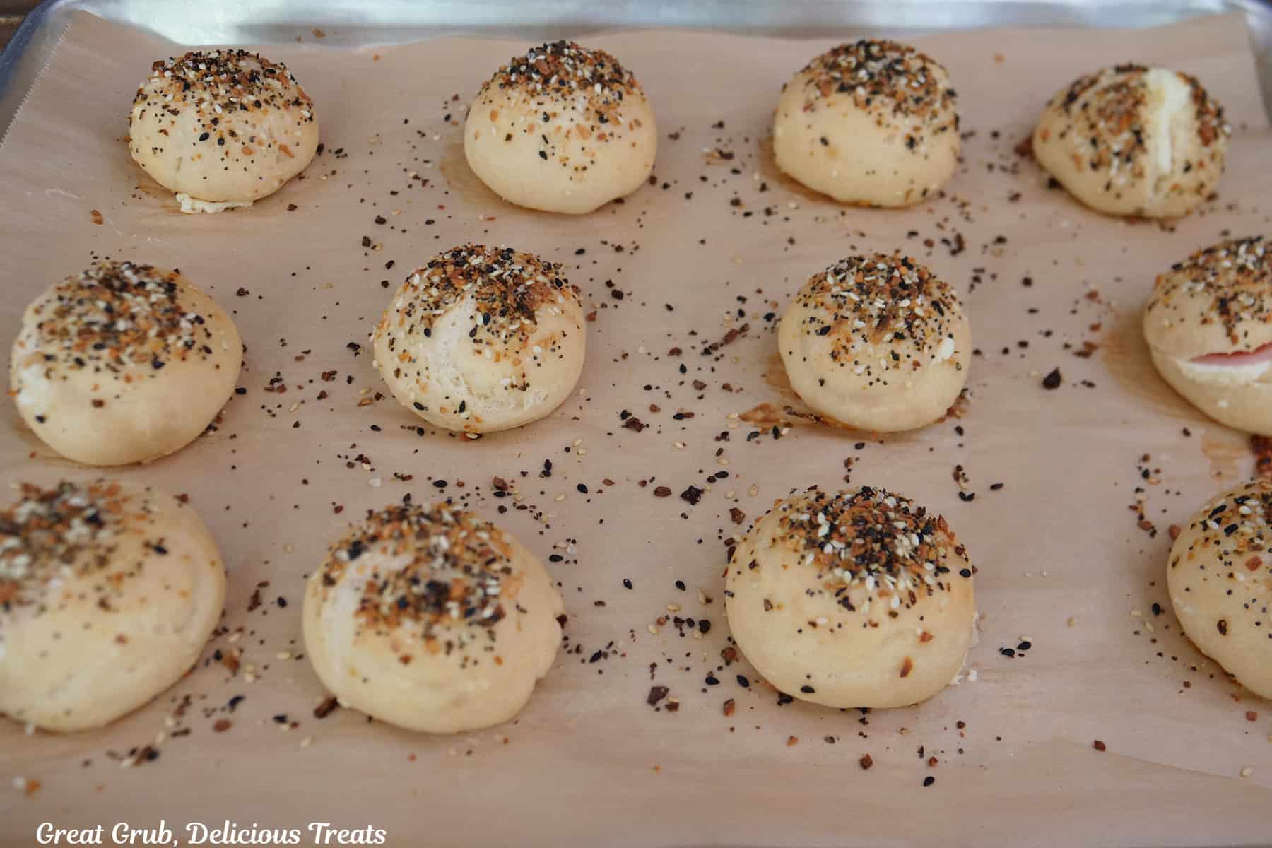 A parchment lined baking sheet with baked bagel bombs on it.