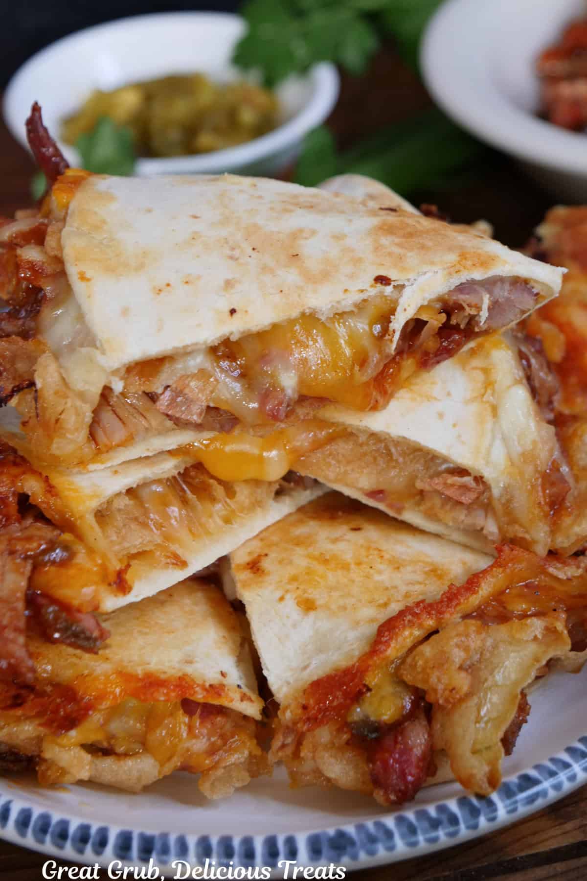 A white plate with blue trim with a stack of quesadilla slices piled on top of each other showing all the ingredients stuffed inside.