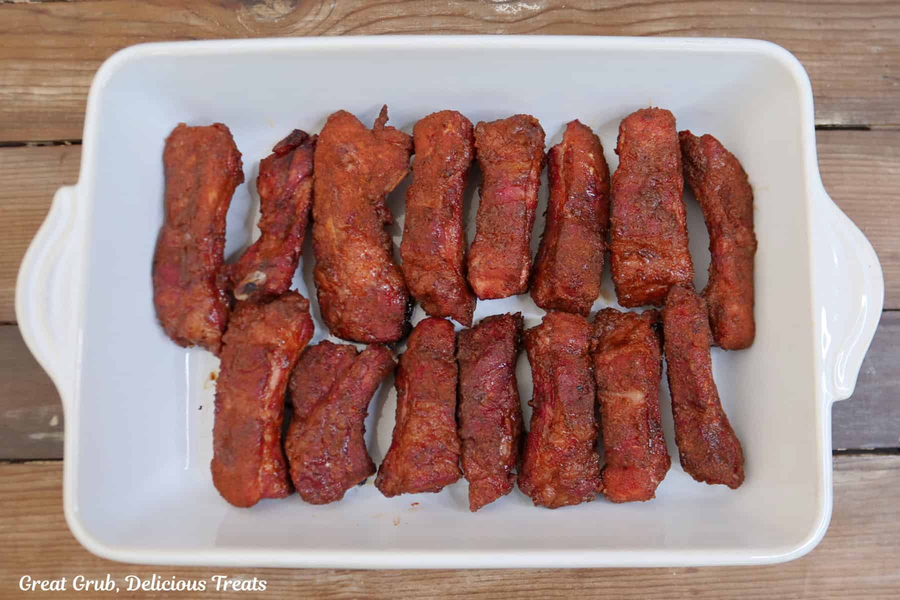 A white 13 by 9 baking dish with the partially smoked ribs in it.