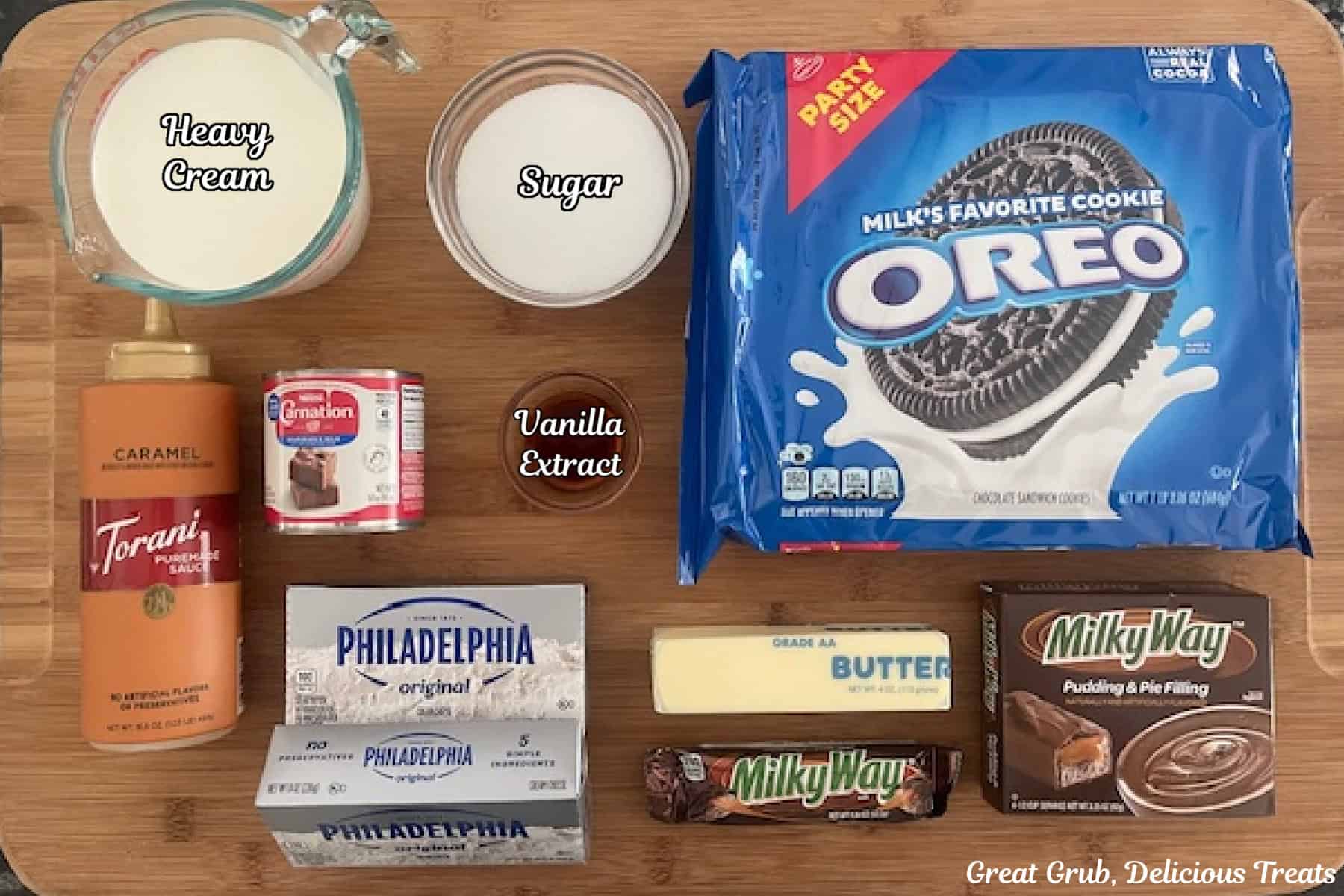 A wood surface with all the ingredients on it to make milky way cream cheese dessert.