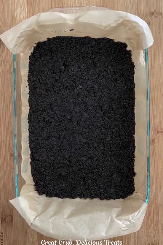 A 7 by 11 glass baking dish with Oreo cookie crust in it before baking.