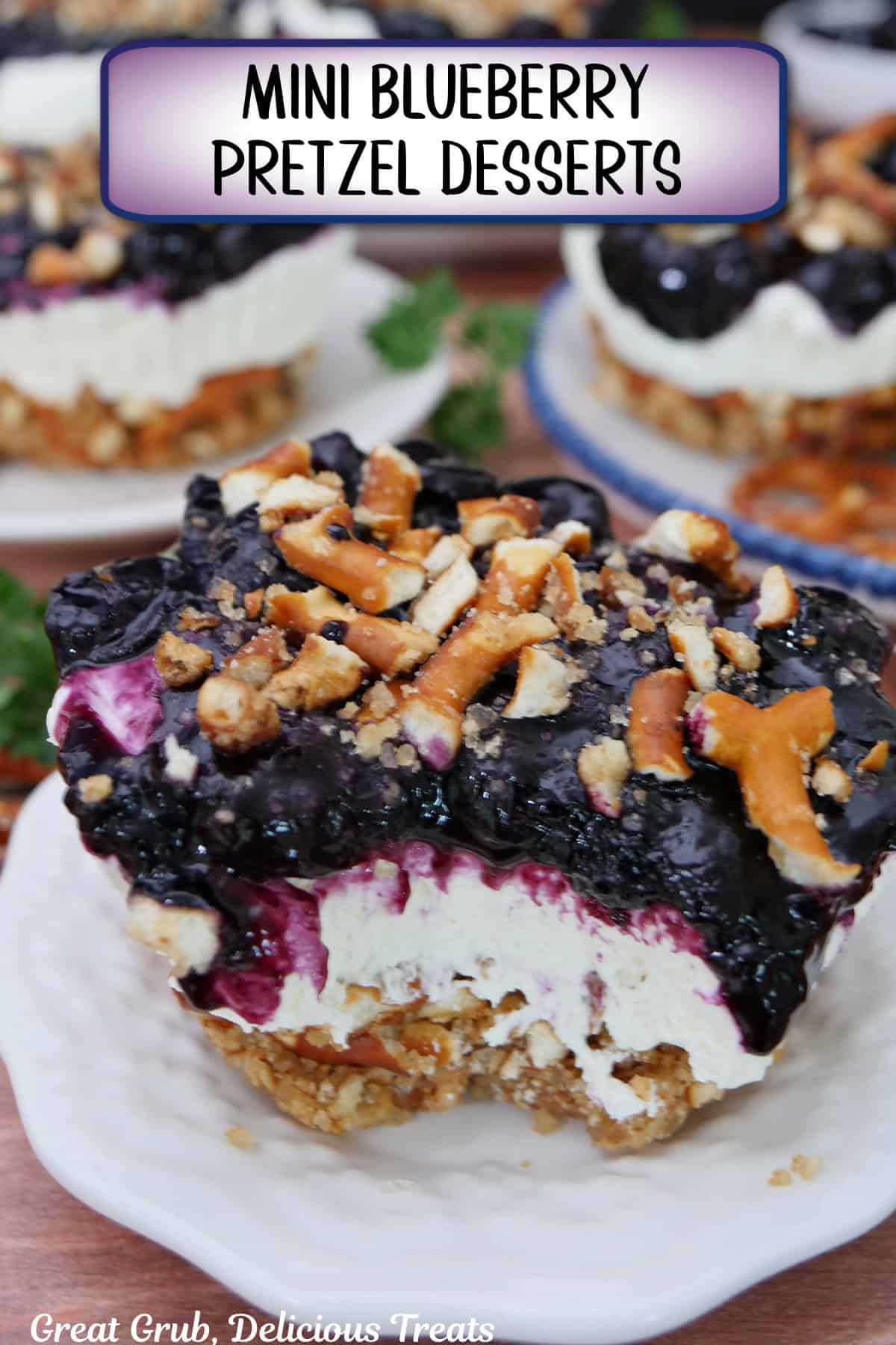 A small round plate with a jumbo mini blueberry pretzel dessert on it with a bite taken out of it, and a title overlay at the top.