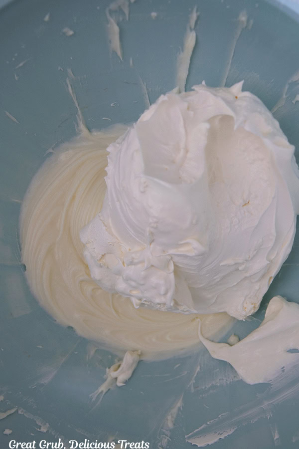 A light blue mixing bowl with a sweet cream cheese filling being mixture together.