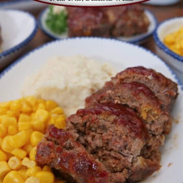 A white plate with blue trim with a sliced mini meatloaf, mashed potatoes, and corn on the plate.