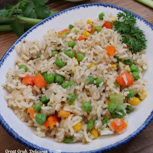 A white bowl with blue trim with a serving of garlic vegetable rice in it.