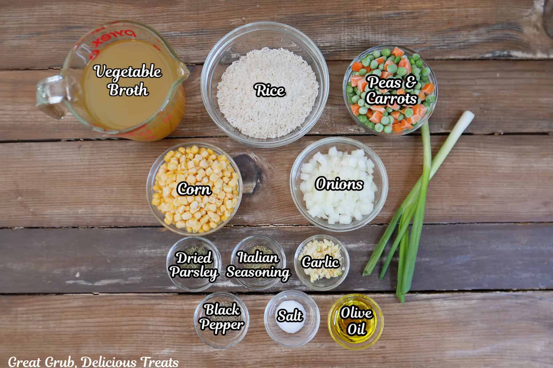 A rustic wood surface with all the ingredients needed to make one-pan garlic vegetable rice placed on it.