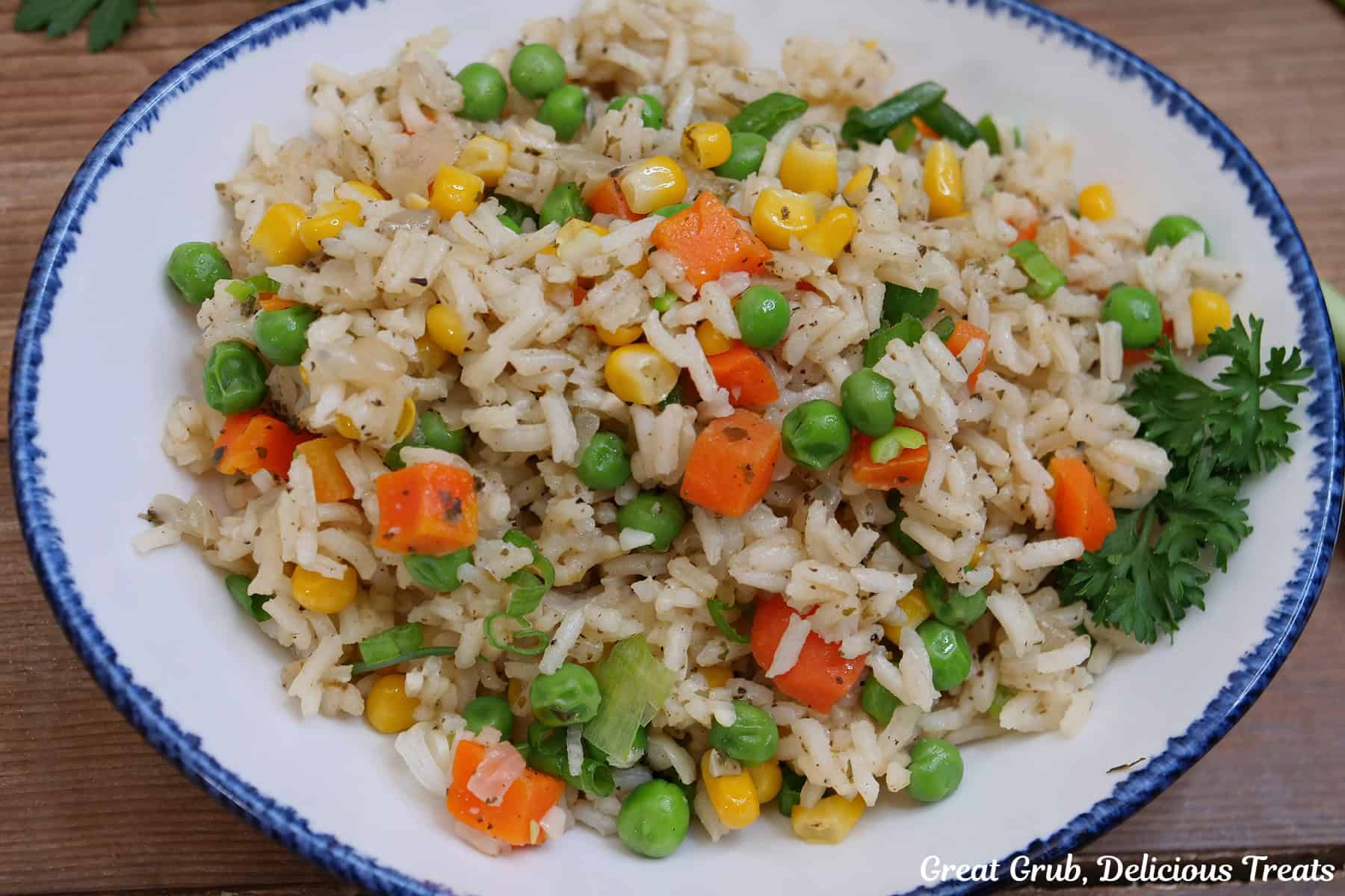 A white bowl with blue trim filled with a serving of garlic vegetable rice.