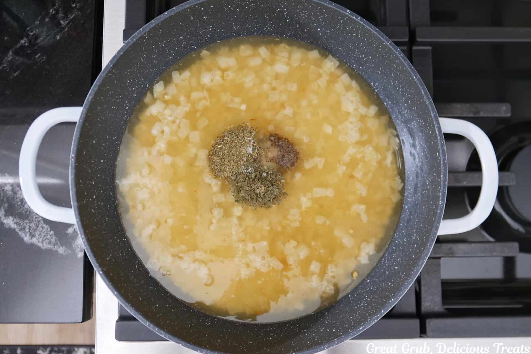 A pan with rice, onions, garlic, chicken broth and seasonings in it.