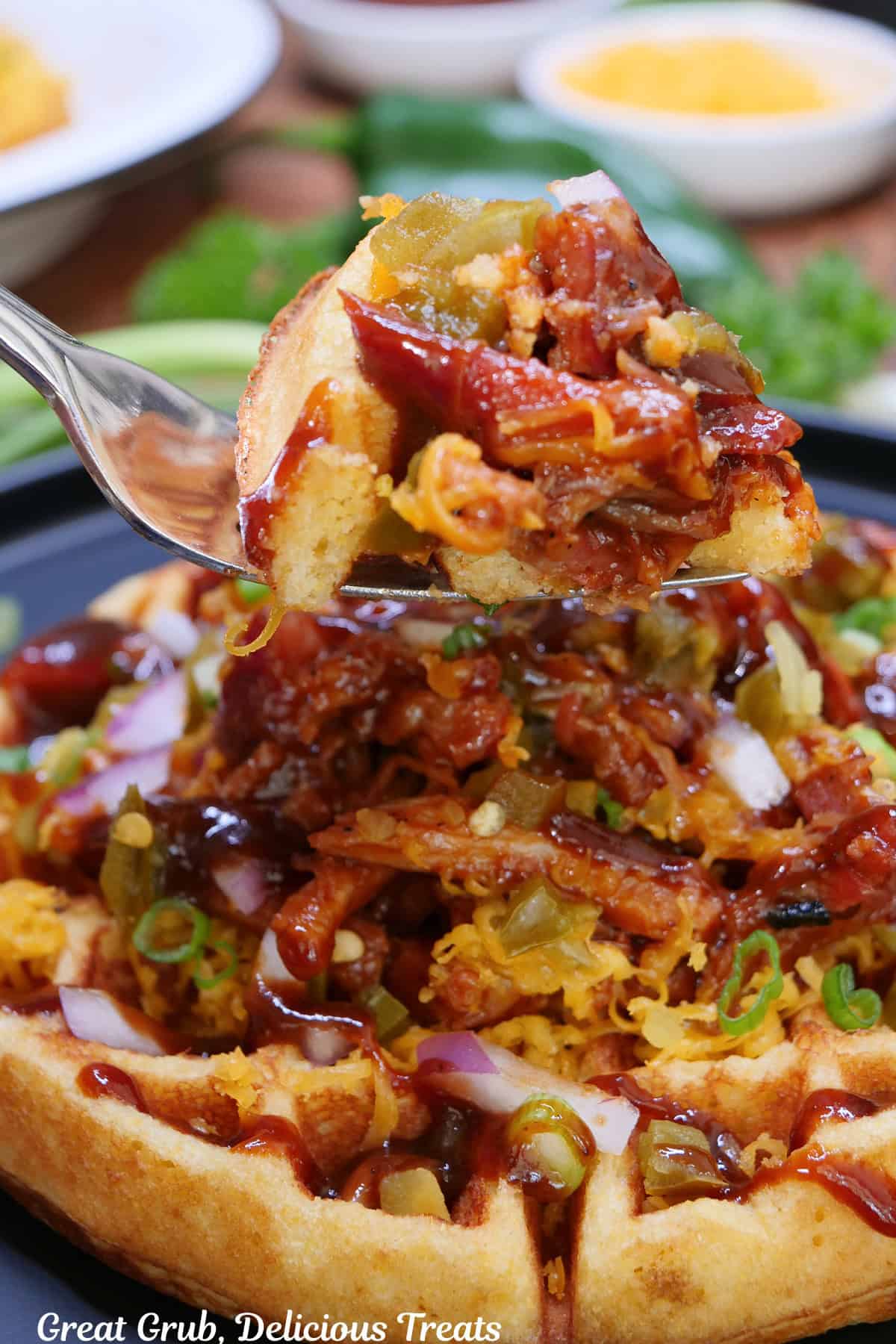 A pulled pork cornbread waffle and a fork held above it with a bite of waffle and pulled pork on it.