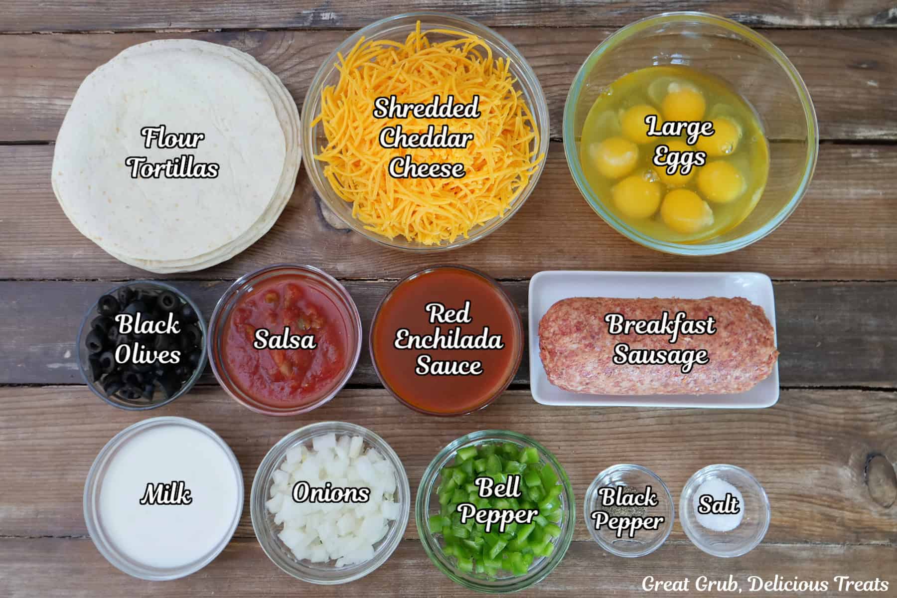 A wood surface with all the ingredients placed on it to make sausage breakfast enchiladas.