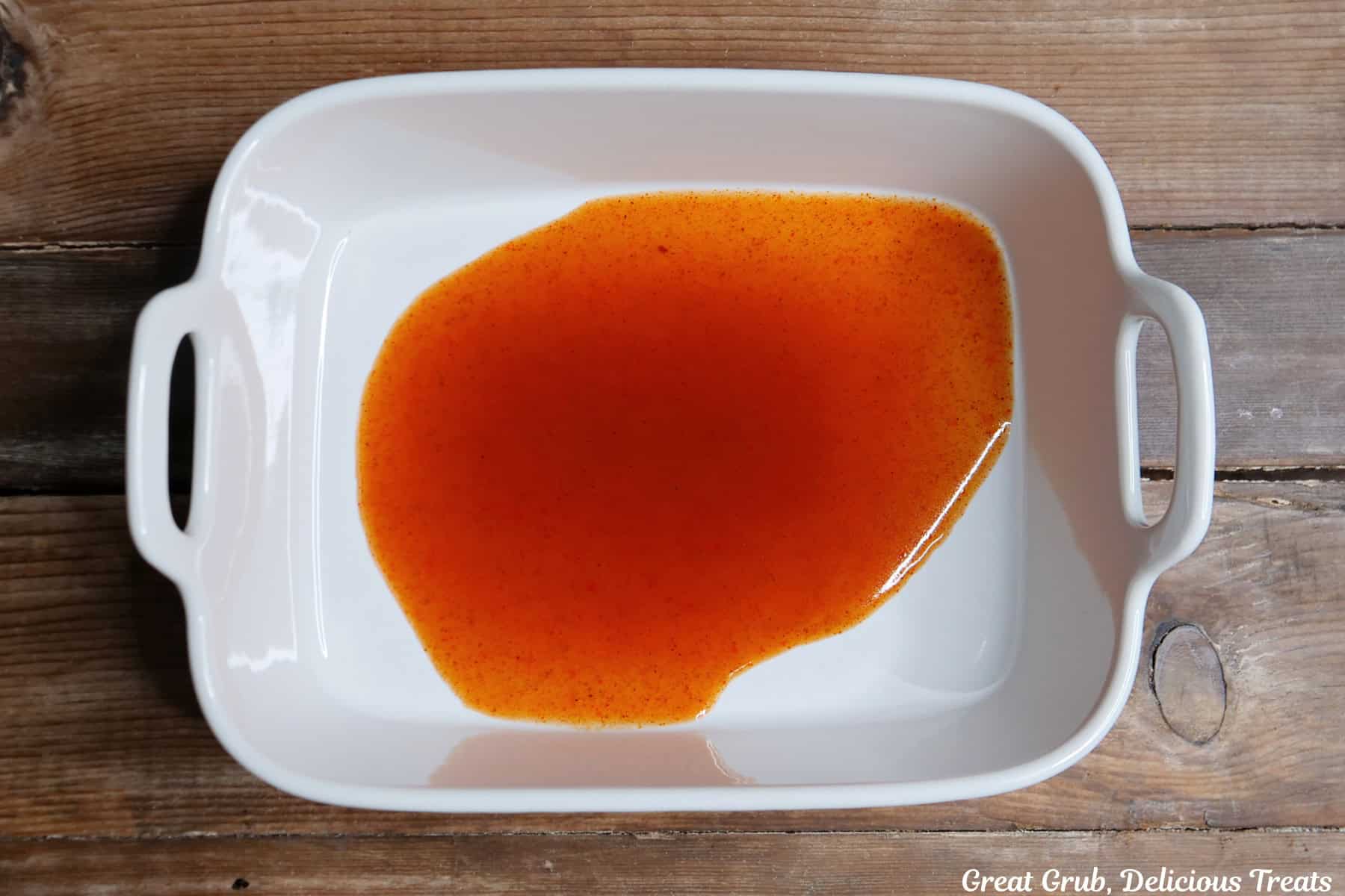A white baking dish with a little bit of red enchilada sauce in the bottom.