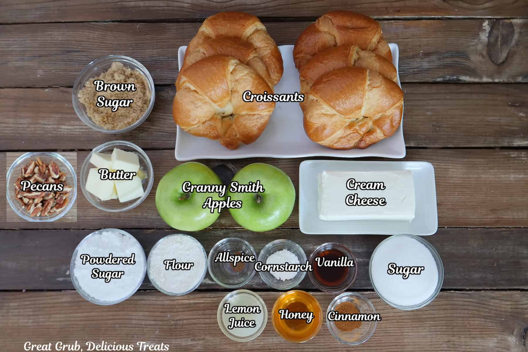 A rustic wood surface with all the ingredients placed on it to make apple cheesecake croissants.
