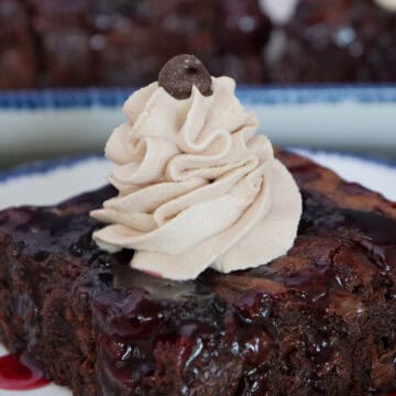 A black forest brownie on a white plate with whipped cream and a chocolate chip on top, and a title overlay at the top.