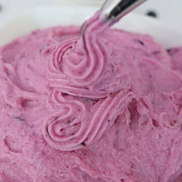 A white surface with a white bowl filled with homemade blueberry buttercream frosting, with a title overlay at the top.