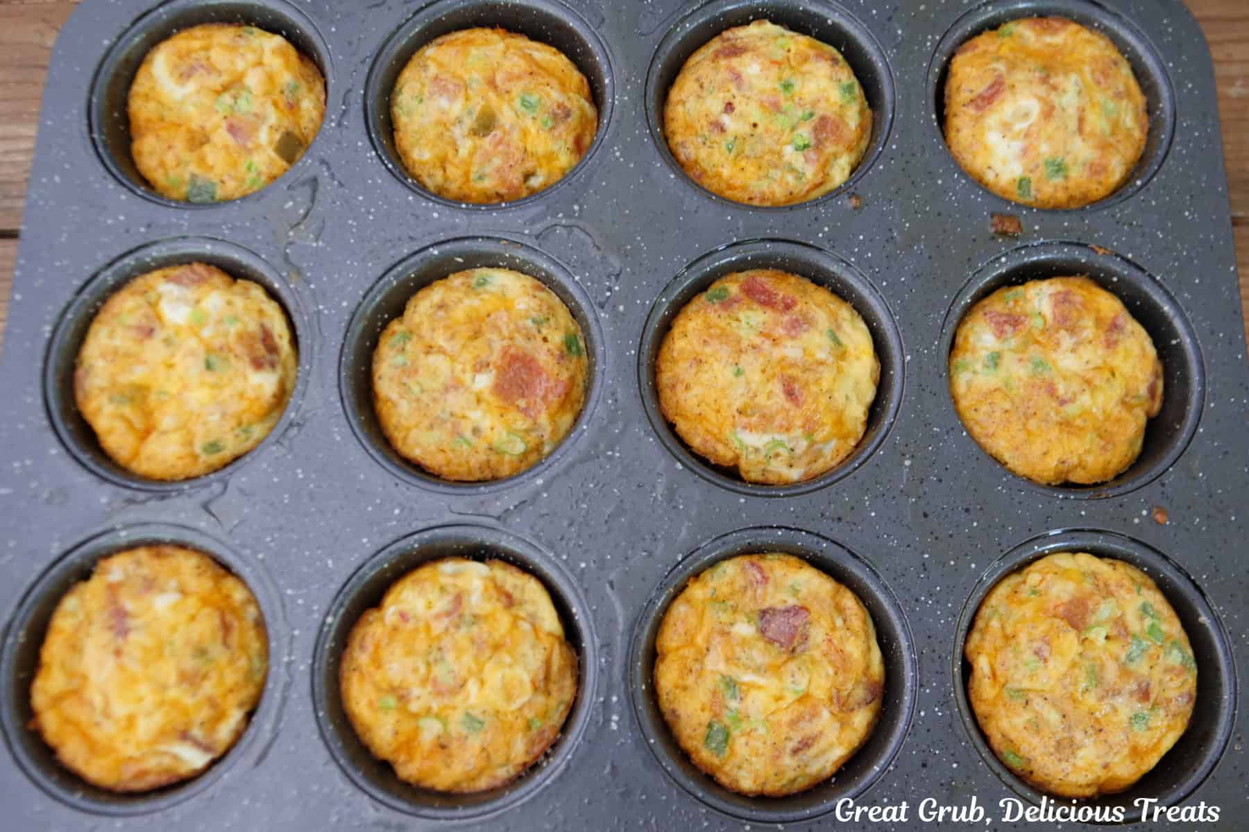 A 12-count muffin tin with baked cheesy egg bites in it.