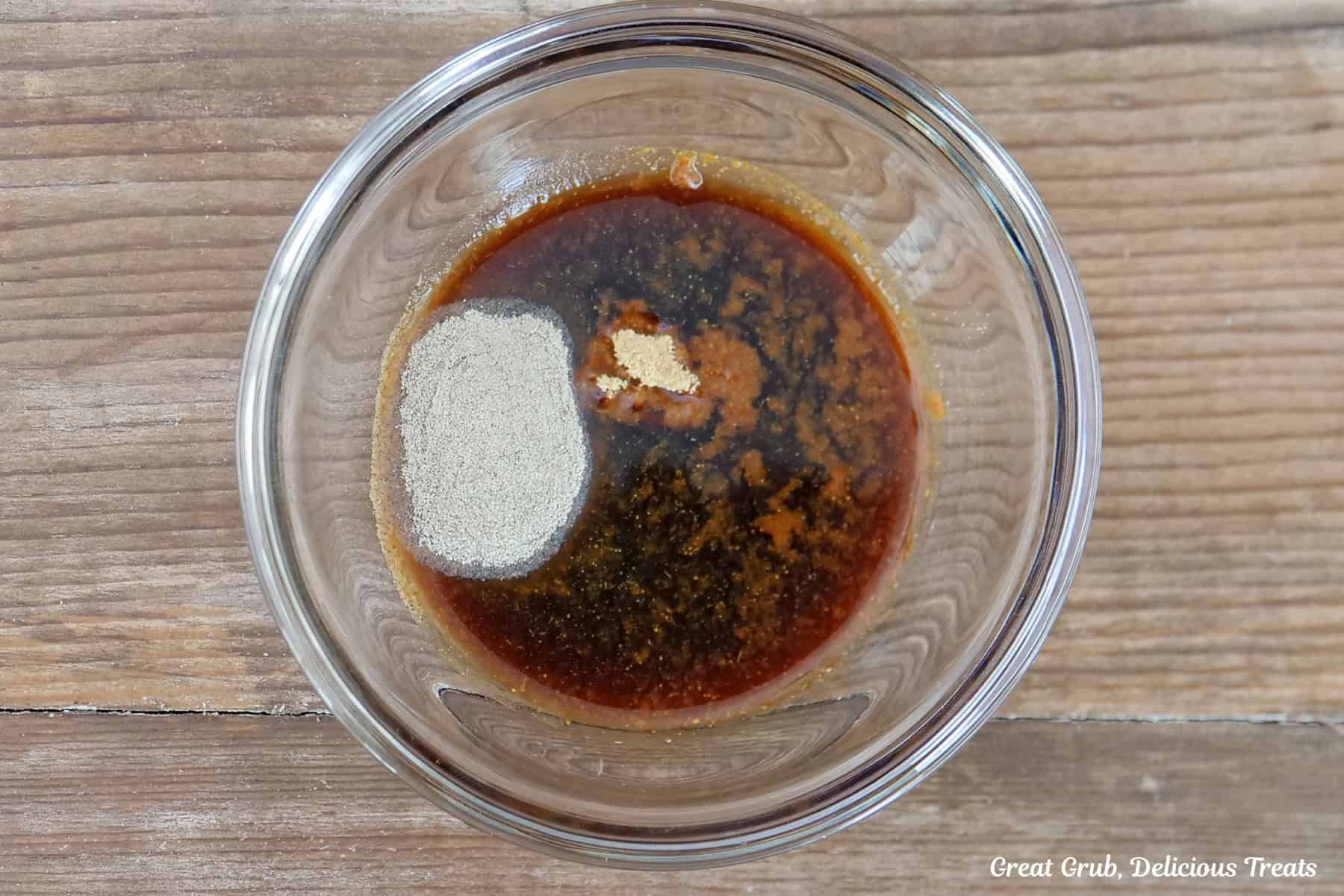 A wood surface with a glass bowl filled with the sauce ingredients for the Hawaiian fried rice.